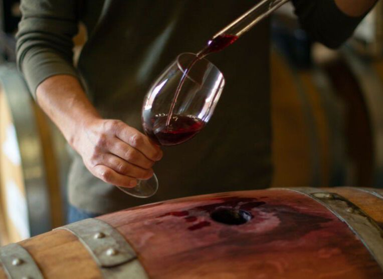 Winemaker pulling wine from barrel